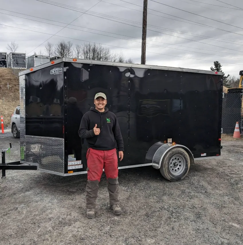 Xavier D. — fondateur d'Eco Pelouse Estrie, devant sa remorque de service à Sherbrooke